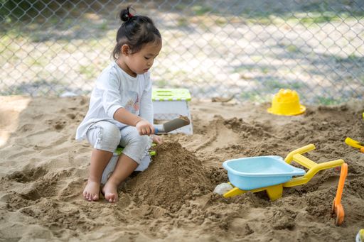 A Southeast Asian female kid playing with sand at the playground
