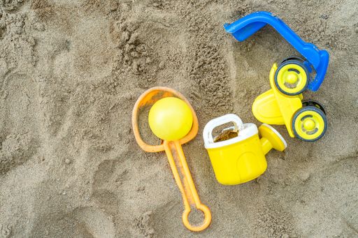 A closeup shot of colorful toys on the sand at the beach