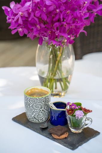 The coffee set served on a white table with beautiful purple flowers in a glass vase