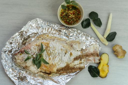 A top view of fresh tasty homemade grilled fish in foil on the table