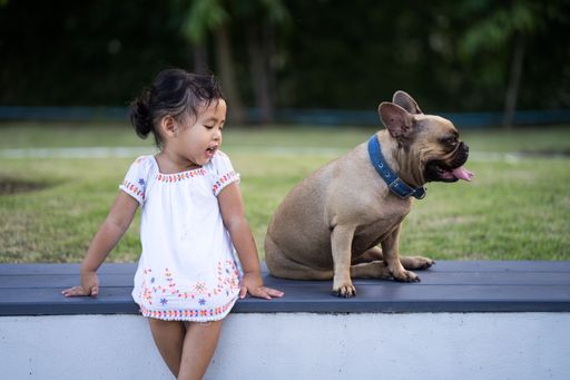 A closeup of a little girl with her dog outdoors.