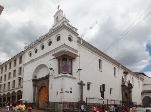 The facade of a typical historical building on a corner of downtown street with people walking around