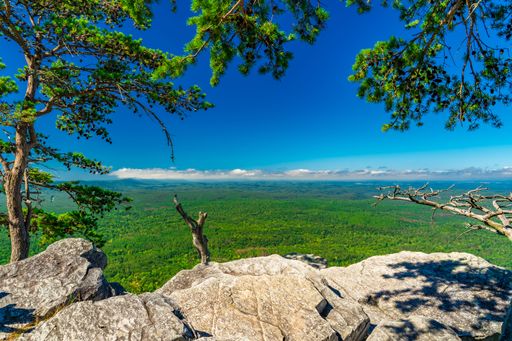 A Pulpit Rock in Cheaha State Park, AL, under a clear blue sky, surrounded by lush greenery