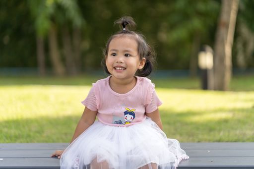 A closeup shot of a Southeast Asian baby girl wearing a cute dress on a blurred background