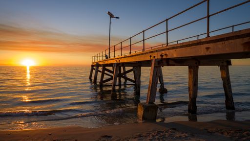 A pier over the calm sea during sunset