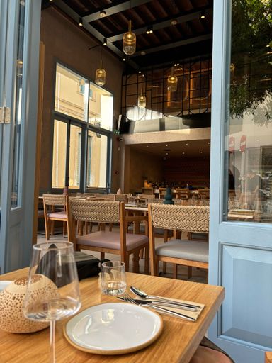 A vertical shot of a cozy interior of a cafe with a warm and welcoming atmosphere, on a sunny day