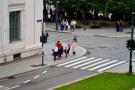 Pedestrians wait for a green light to cross the road by Domus Bibliotheca, one of the university buildings along Karl Johans gate in Oslo, Norway.