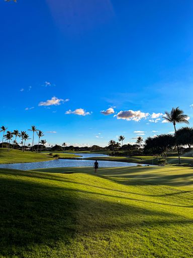 A woman walking on a golf course on a sunny day.
