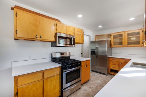 An interior view of a renovated modern kitchen with wooden cabins and white walls illuminated with bright light
