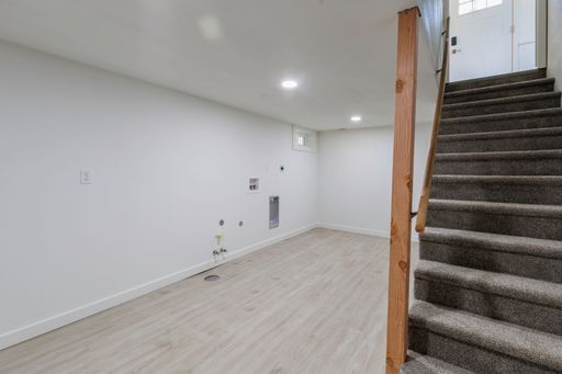An interior view of a staircase in a renovated empty room with wooden parquet flooring and white walls