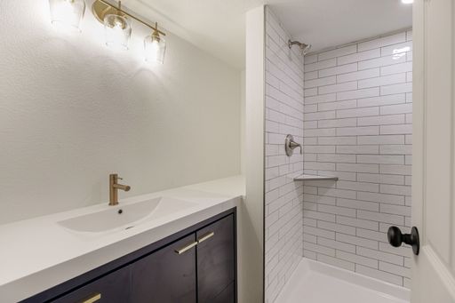 An interior view of a modern sink and shower cabin in a small bathroom, illuminated with bright light