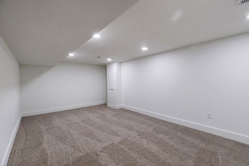 An interior view of a new, renovated empty room, with white walls, carpet flooring illuminated with bright light