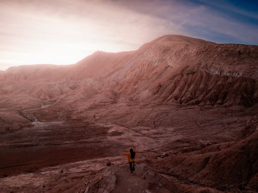 A young Hispanic woman watching the scenery of San Pedro de Atacama desert at sunset in the Andes mountains of northeastern Chile