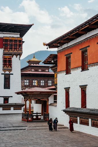 A Tibetan Buddhist monk and worshipers at the Tashichho Dzong. Bhutan