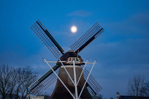 A windmill on Ameland island in the Netherlands under a moonlit evening sky