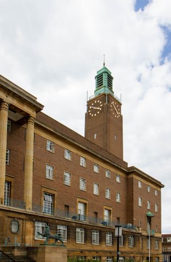 The historical clock tower of the Norwich City Hall under the cloudy blue sky in Norwich, United Kingdom
