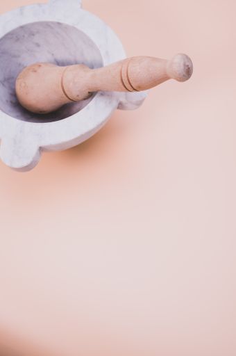 A vertical shot of wooden mortar and marble pestle isolated on light brown background