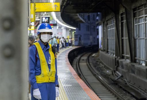 Photo of a JR staff member waiting for oncoming train at a railway station in Tokyo