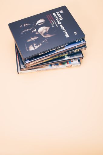 A pile of Italian DVD and blu-ray films isolated on light brown background with copy space