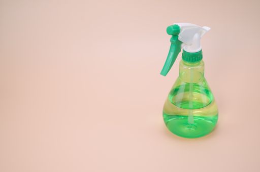 A closeup shot of green plastic spray isolated light pink background