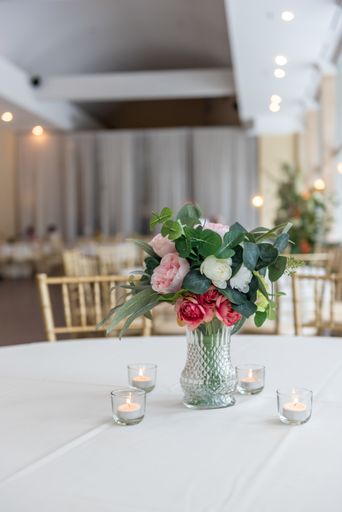 A vertical closeup shot of a vase with a beautiful bouquet surrounded by candles on the table