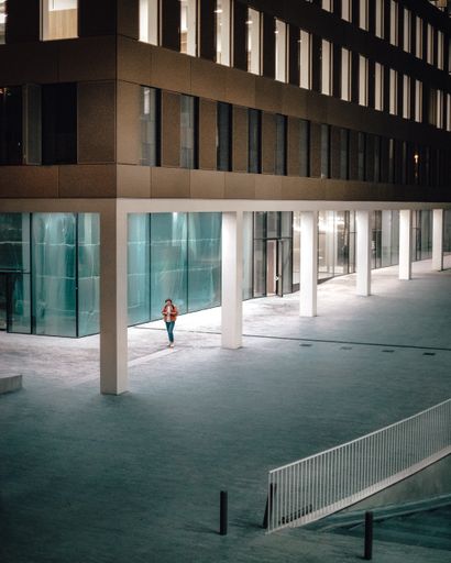 A vertical shot of a lonely man walking at night in the Post X area in Antwerp