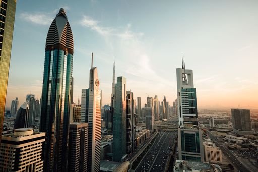 A stunning aerial view of Dubai's modern skyline at sunset, showcasing iconic skyscrapers and busy highways.