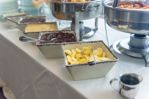 A high angle shot of bowls of fruit and jams on the table of a restaurant
