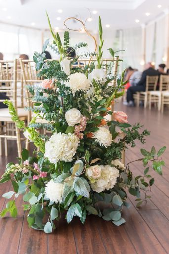 A vertical closeup shot of a white and pink flower bouquet in a wedding hall