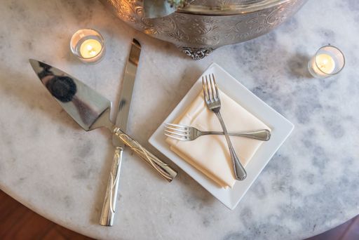 A high angle closeup shot of silver cake knives, forks, and candles on the table