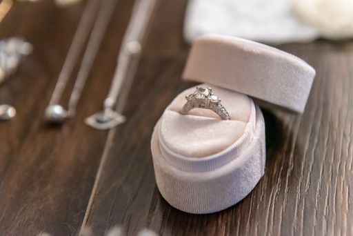 A selective focus closeup shot of a bridal wedding  ring gently placed in a light pink box with a removed cover surrounded by other jewels