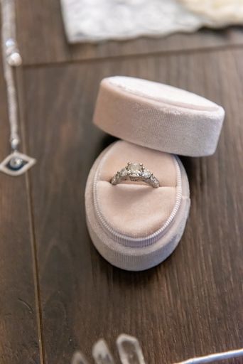 A vertical closeup shot of a wedding ring in a white box on a wooden surface