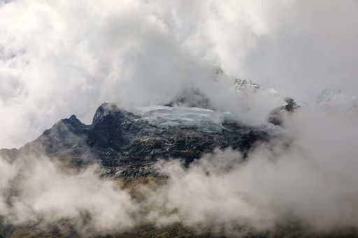 A stunning view of the snow-capped Salkantay Mountain peak with clouds against a clear blue sky.