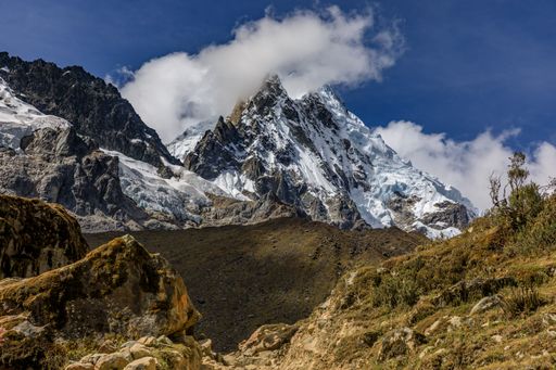 A stunning view of the snow-capped Salkantay Mountain peak with clouds against a clear blue sky.