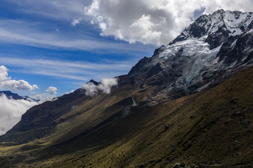 A stunning view of the snow-capped Salkantay Mountain peak with clouds against a clear blue sky.
