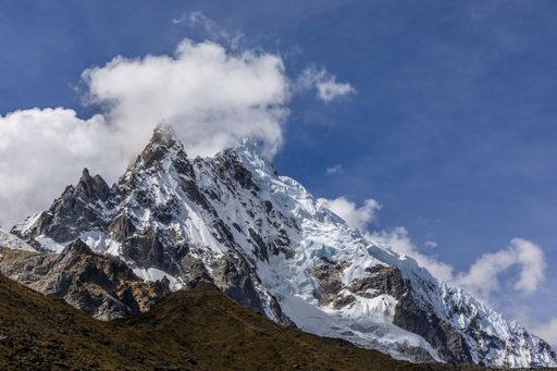 A stunning view of the snow-capped Salkantay Mountain peak with clouds against a clear blue sky.