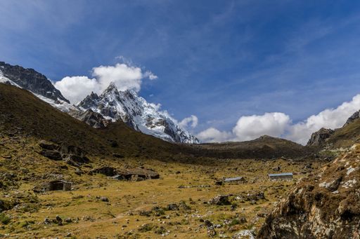 A stunning view of the snow-capped Salkantay Mountain peak with clouds against a clear blue sky.