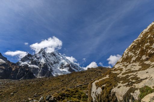 A stunning view of the snow-capped Salkantay Mountain peak with clouds against a clear blue sky.