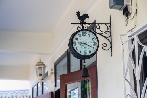 An outdoor or wall clock in the area of a terrace at a house in a street