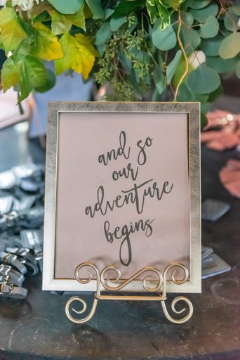 A vertical closeup shot of a frame with the writing "and so our adventure begins"