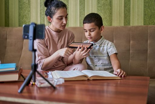 A young female teacher explaining the math lesson with a young pupil during an online class