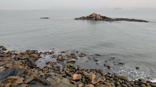 A serene coastal scene with a rocky shoreline and a calm ocean