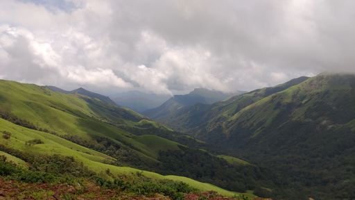 A scenic view of lush green mountains under a cloudy sky, showcasing the beauty of nature.