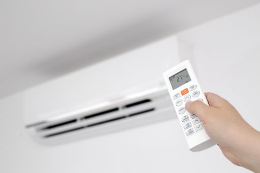 Close up of a Female Hand operating a Remote control of a Domestic Air conditioner unit of a modern house