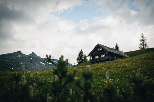 A closeup shot of a cottage house on the hill covered in greenery