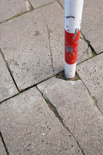 A vertical high angle shot of a metal pole in between concrete tiles