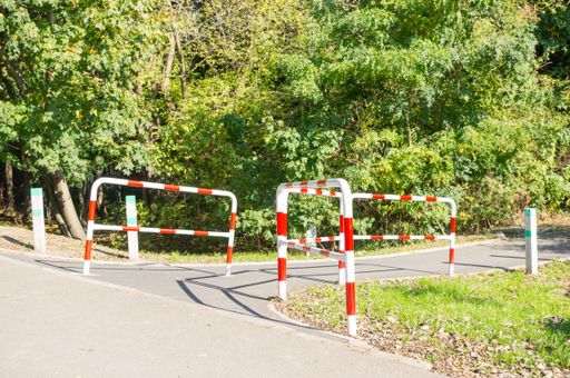 The metal traffic barrier on the road with trees in the background