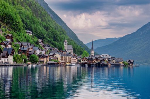 A beautiful view of Hallstatt village with traditional houses and a church by the lake surrounded by lush green mountains in Austria.