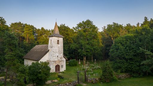 Aerial view to the historic small chapel with the thatched roof and wooden top of the bell tower on the coastal cemetery in Hiiumaa island, Estonia