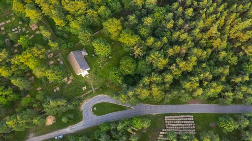 Aerial view to the historic small chapel with the thatched roof and wooden top of the bell tower on the coastal cemetery in Hiiumaa island, Estonia